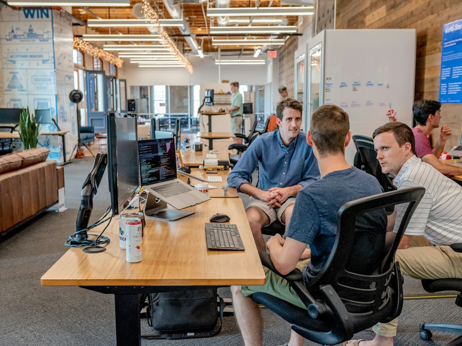 Three colleagues working at their desks across different systems