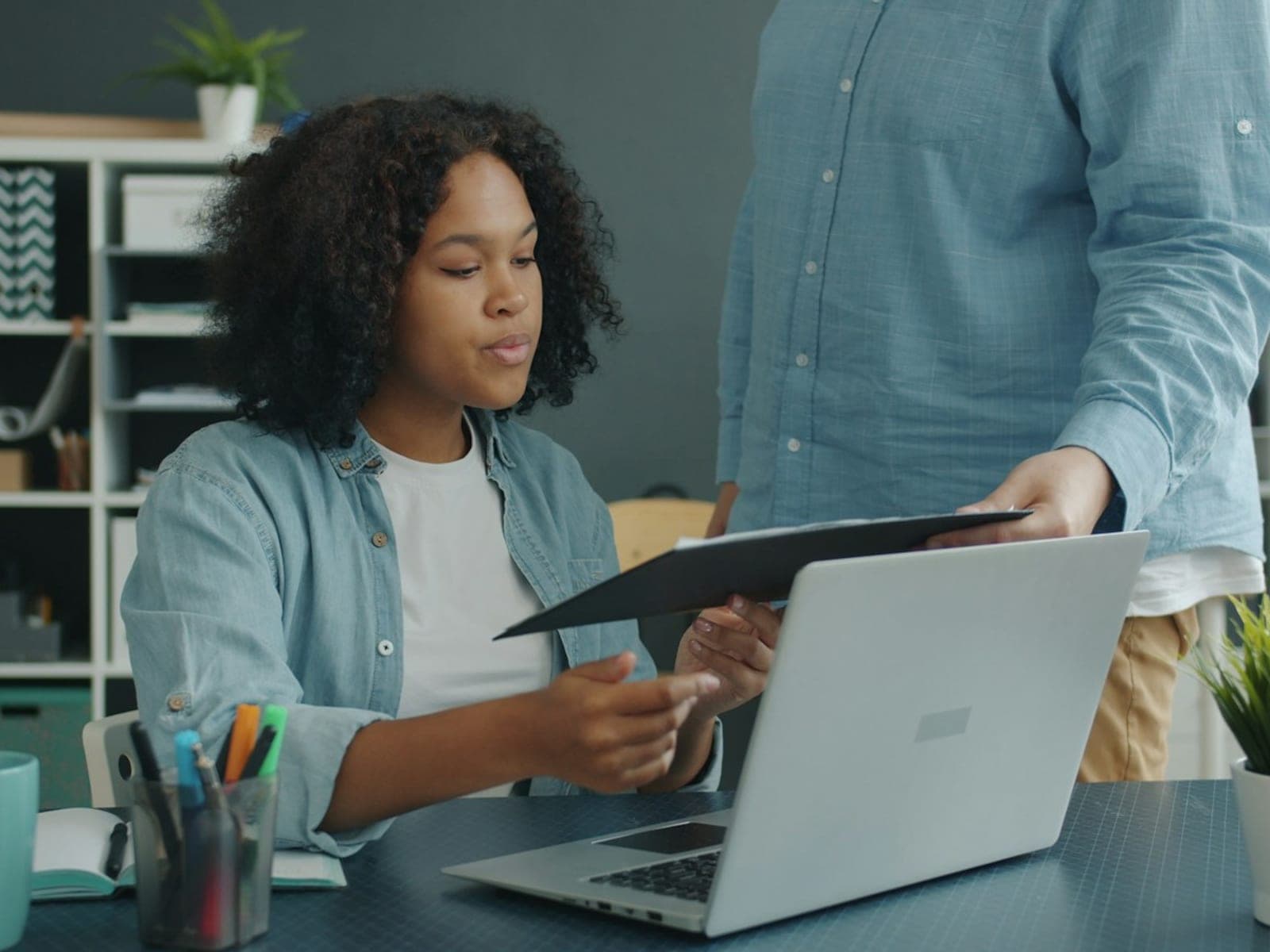 Two colleagues going through a weekly report at an office desk