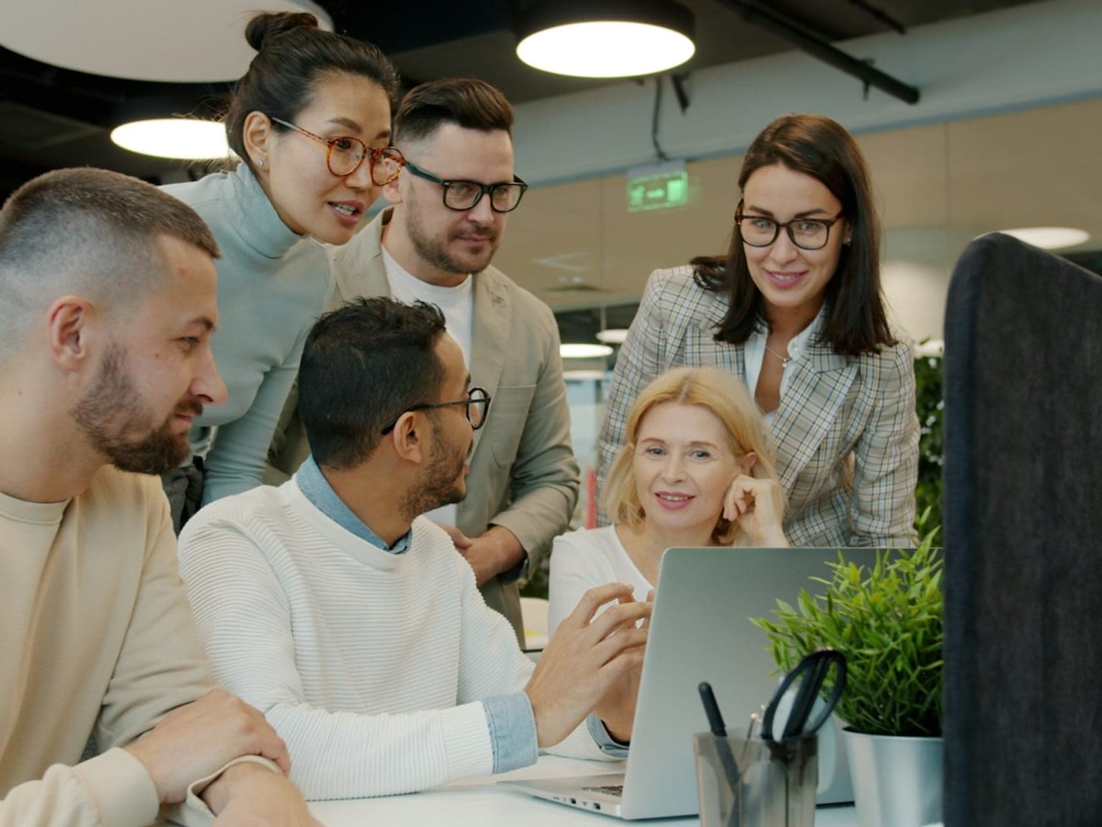 A diverse team gathered around a laptop planning their week