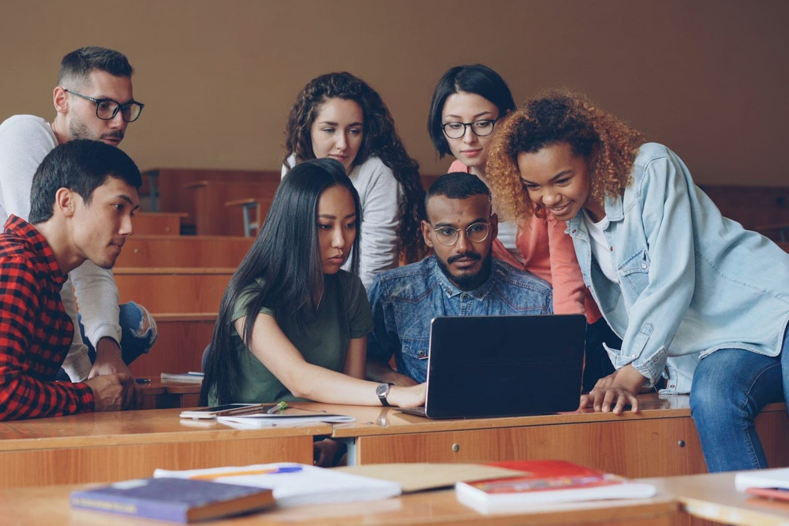 A diverse group of students working together around a laptop